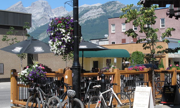 Summer street scene with flowering baskets, bicycles and outdoor seating, with mountains in the background