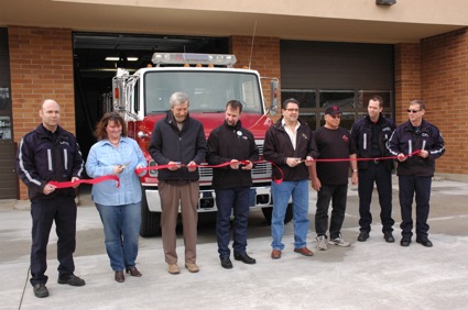 people cutting a ribbon in front of a building.