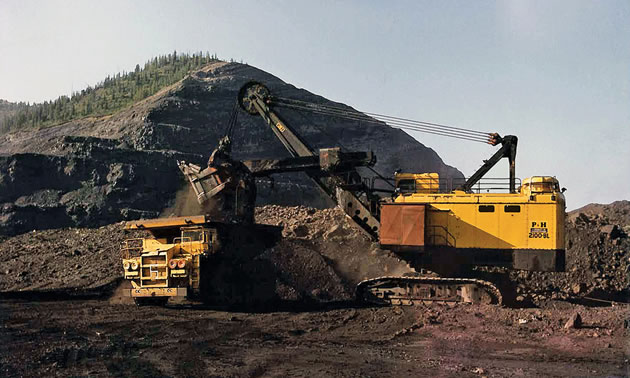 A yellow Teck truck shovel in front of a large coal pile