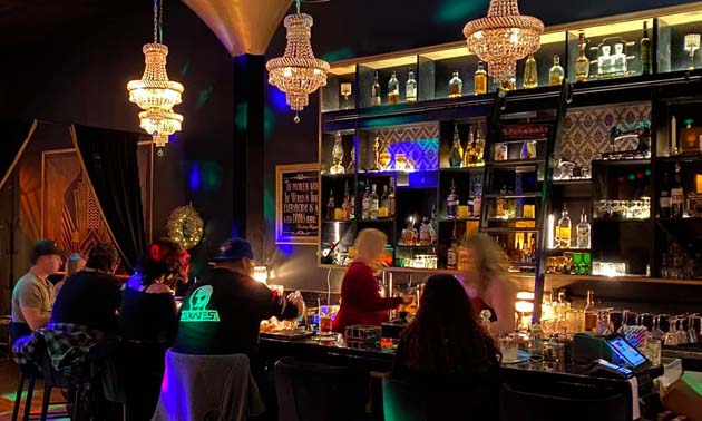 Interior of Frisky Whisky Tapas Lounge, showing bar area and three art-deco style lights above bar. 