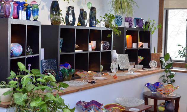 Shelves of brightly coloured glass items line shelves.