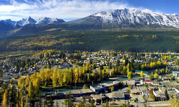 The small town of Golden, interspersed with greenery, is set against a blue and white mountain backdrop. 