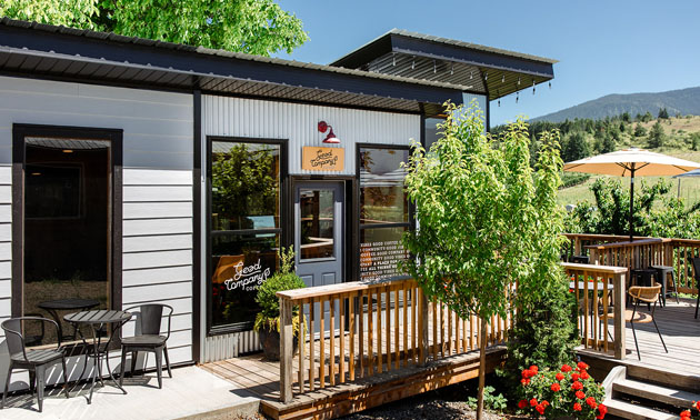 Exterior of Good Company Coffee, white siding on building, dark wood trim. Small patio out front. 