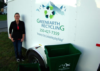 Young woman in her twenties posing beside recycling trailer and plastic bins