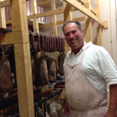 Master butcher Uwe Gwinner is explaining the aging process, with meats hanging in the room.