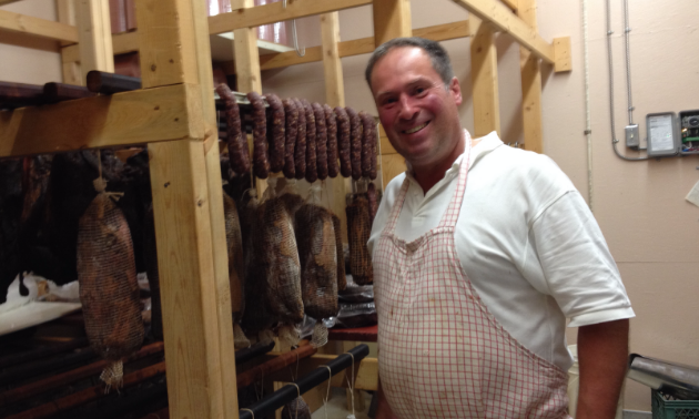 Master butcher Uwe Gwinner is explaining the aging process, with meats hanging in the room.