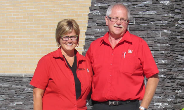 Walter and Heather Ingram, wearing their red Home Hardware shirts, stand in front of their new building.