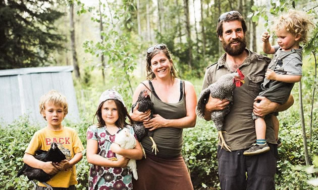 Parents are standing with their three kids on their farm.