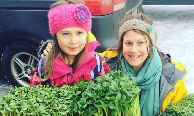 Mother and daughter are carrying trays of greens for the farmers market.