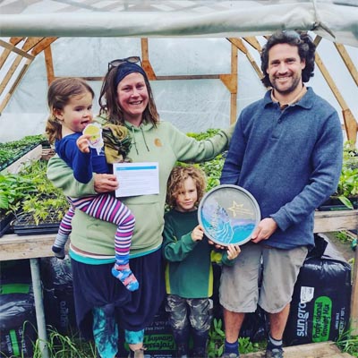 Owners of Happy Hills Farm standing in greenhouse with kids. 
