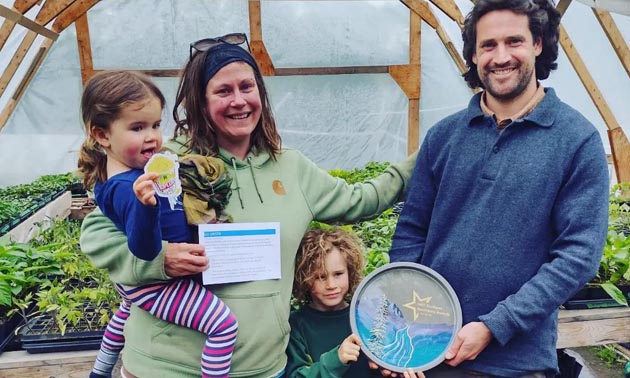 Owners of Happy Hills Farm standing in greenhouse with kids. 