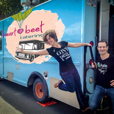 The Heartbeet Catering food truck is a brilliant light blue, with the owners, Michel Kuhn and Nicole Vogt, standing nearby.