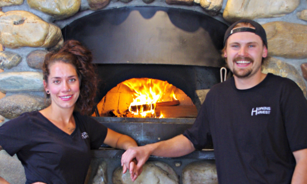 Kerstan Hopkins and boyfriend Matthew Larsen, co-operators and managers of Hopkins Harvest, pose next to the gourmet wood-fired pizza oven.