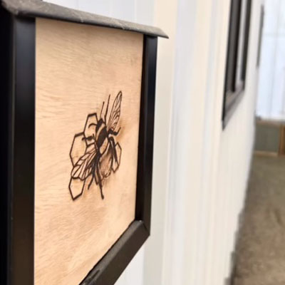 Graphic design of bee on side of tiny home building. 