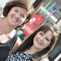 Michelle Hansen and Wendy Franz stand outside their Imagine Ink store.