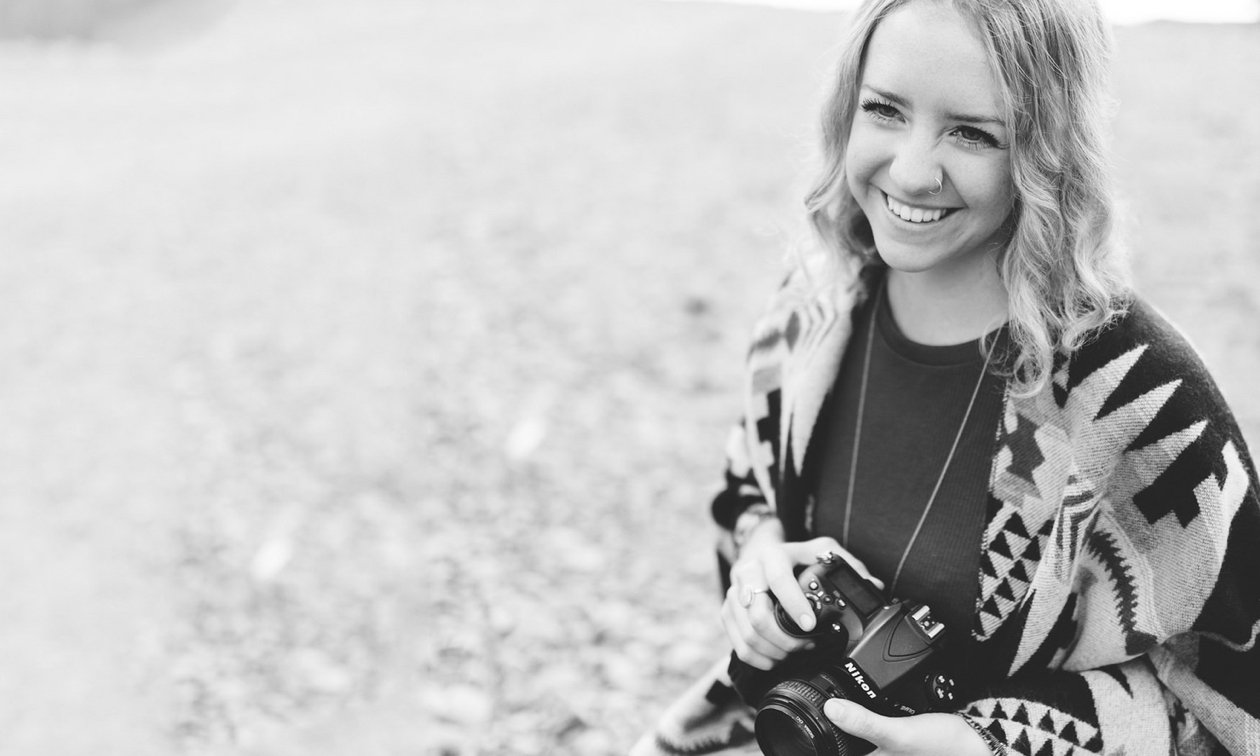 Jacey Paton in a field, smiling with her camera