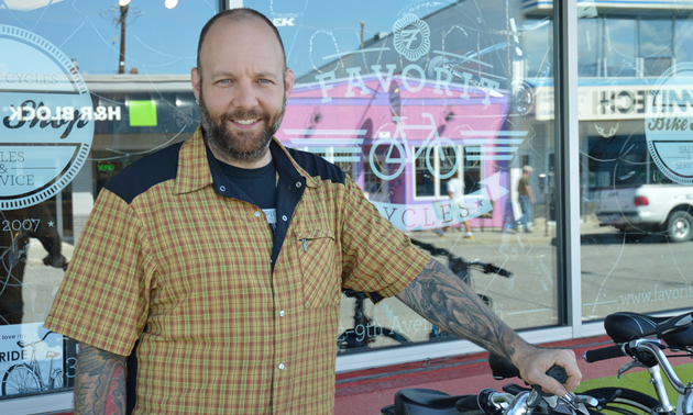 Smiling bearded man with bicycle outside showroom window
