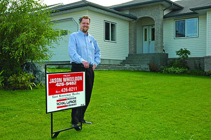 Man with for sale sign in front of home