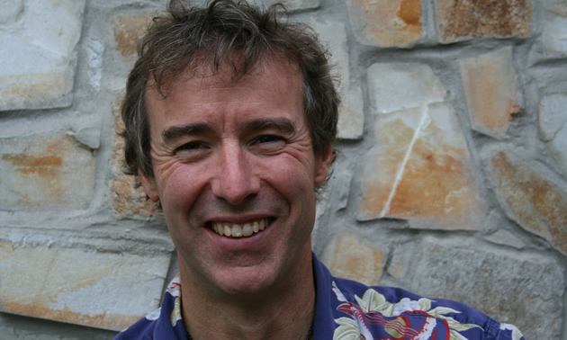 Head-shot of smiling, outdoorsy-looking middle-aged man wearing a flower-patterned shirt