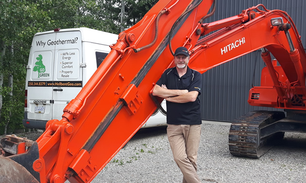 John Managh, co-owner of Hellbent Geothermal, stands in front of a large piece of machinery.