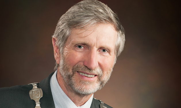 Head-shot of lean, grey-haired, bearded man in business dress, with a chain of office around his neck