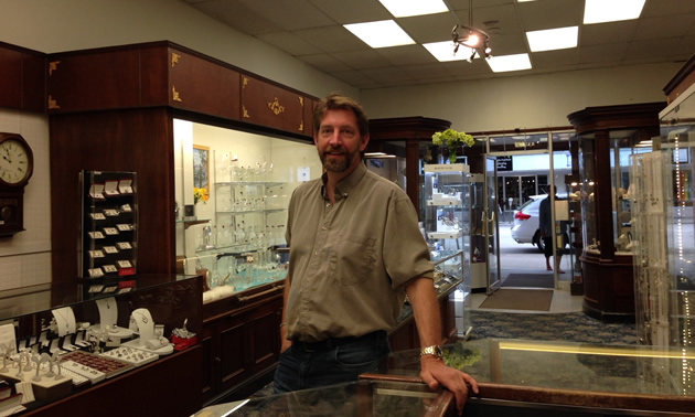 Justin Pelant, gemologist, stands beside display cases inside his store. 