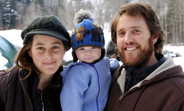 Caley (Left), Torin and Andrew Bennett this past winter with goat barn and market gardens in background