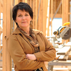 Woman stands, arms folded, inside a building under construction.
