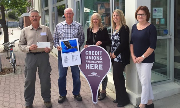 Kootenay Savings Kimberley Branch employees Dawn Marchi, Leanne Perrault and Susan Cleverly present Neal Weisenberg and John Lyon of the Kimberley Camera Club with a $750 cheque to help the Club purchase new equipment.