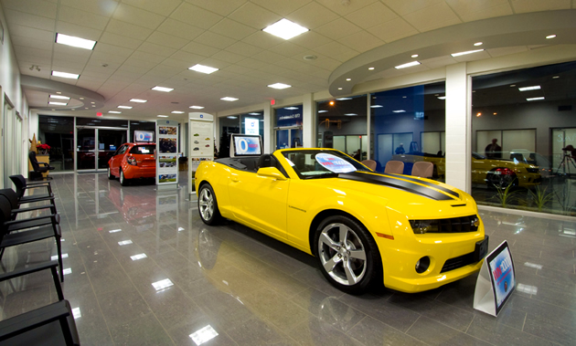 A show room showcases a yellow convertible. 