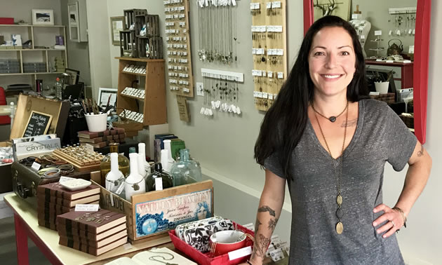 Owner Kara Clarke is standing in her store in front of lots of jewelry.