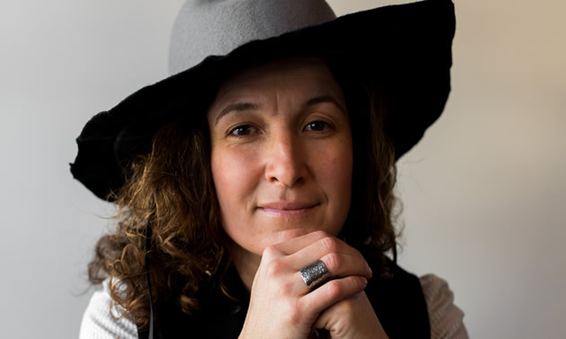 Kat Cadegan, jewelry designer, poses wearing a wide-brimmed hat
