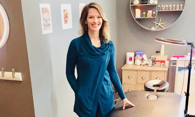 Katherine Spring is standing next to an examination table where she serves her clients.