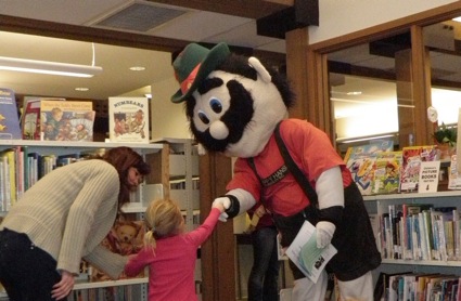 A dressed-up mascot greets a kid.