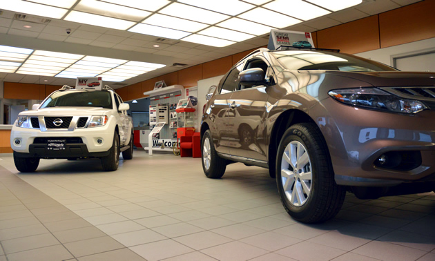 Two shiny Nissan cars are displayed in a showroom.