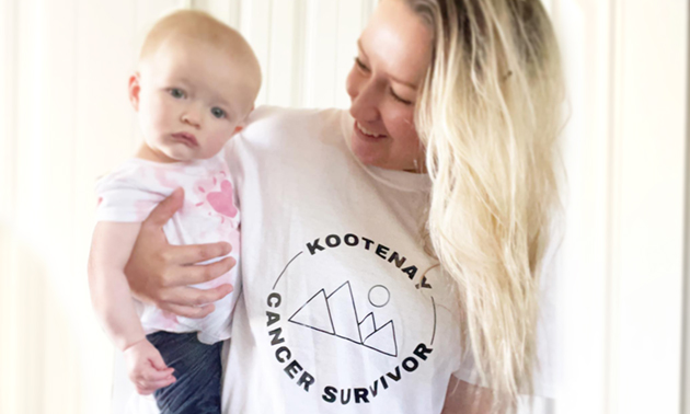 Karli Melnychuk wearing Kootenay Cancer Survivor t-shirt and holding her baby girl. 
