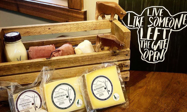 Display of goat milk cheese, assorted meats in basket. 