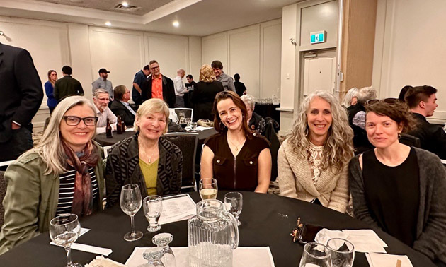 Group of ladies from Kootenay Career Development Society sitting at table celebrating. 