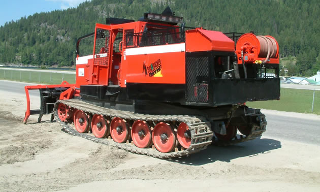 A large orange machine, seen from the back, has tracks and reads 