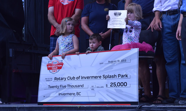 Three children display a large cheque in the amount of $25,000