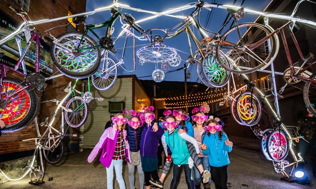 Children standing under an arts installment at night