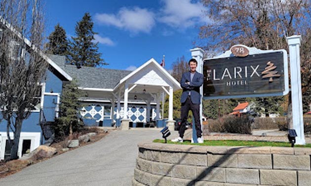 Joseph Raymond standing in front of Larix Hotel sign. 