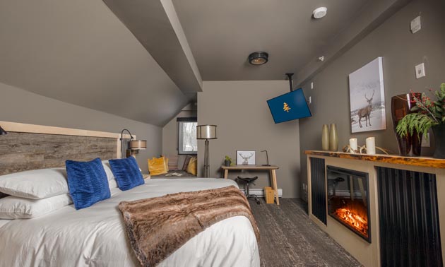 Room with custom-built bed, fireplace, grey walls, TV in corner. 
