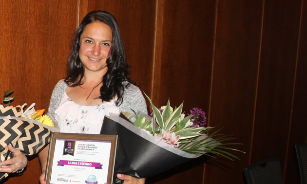 Lilina Lysenko holds a congratulatory bouquet and a certificate recognizing her as a 2019 influential woman in business