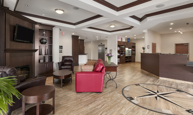 A tile floor has a compass design, there is a front desk, a paneled roof, a red chair, and other amenities. 