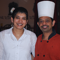 Smiling woman in white shirt and man in red shirt and chef hat