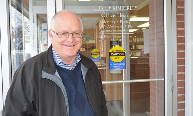 Smiling senior man at the glass doors of Kimberley City Hall