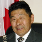 Close-up photo of Asian man in a dark suit, tie and white shirt