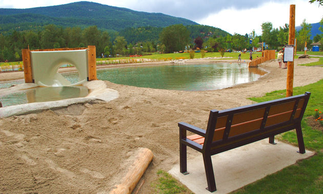 A bench overlooking the bottom pond and water slides at the Millennium Park Natural Outdoor Swimming Ponds project in Castlegar, B.C.
