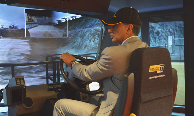 Government Minister Amrik Virk operates a haul truck simulator.